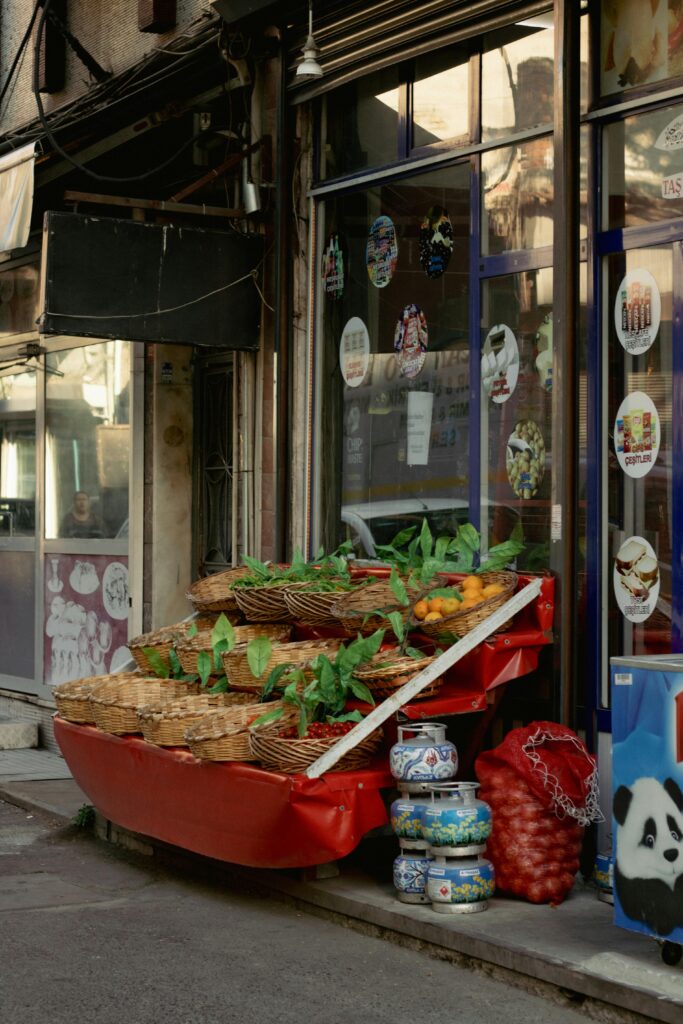 Colorful grocery store entrance with fresh produce and baskets in an urban setting.
