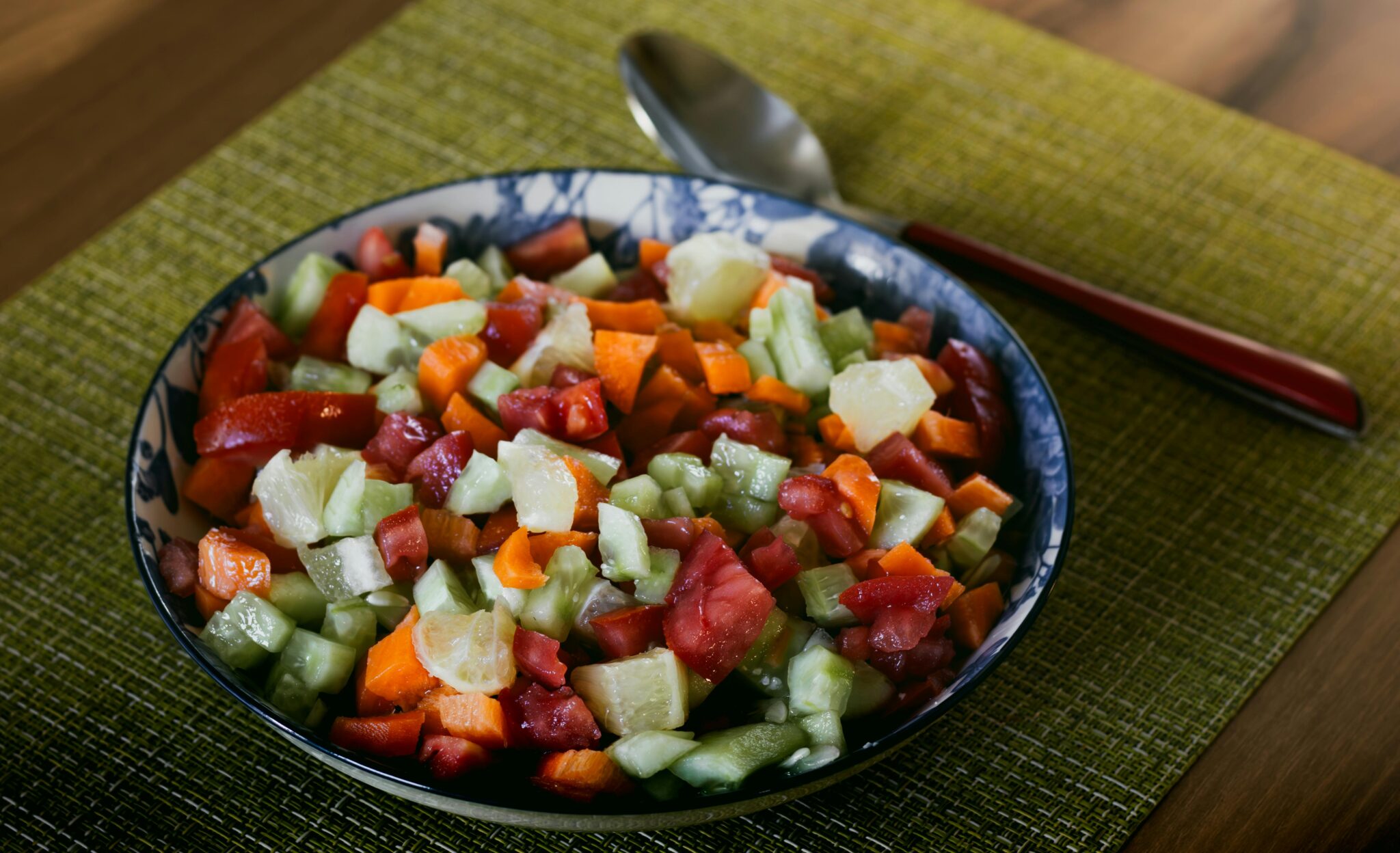 Colorful and healthy vegetable salad in a decorative bowl on a wooden table.